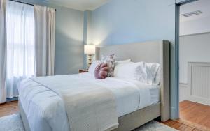 una camera da letto con un grande letto bianco con cuscini bianchi di The 200 South St - King Rm 22 a Charlottesville Altre 27 foto