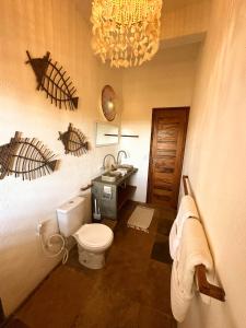a bathroom with a toilet and a sink and a chandelier at Casa Tartaruga Emboaca Trairí in Trairi