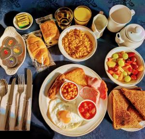 a table topped with plates of breakfast food with eggs and bread at Rossdene House in Blackpool