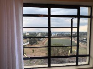 een raam met uitzicht op een veld dat er doorheen kijkt bij The R&M Escapes in Kisumu +2 foto's