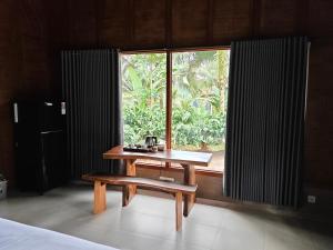a table and a bench in front of a window at Olimpus ecolodge in Tabanan