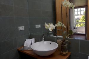 baño con lavabo blanco y espejo en Pensión O Xardin de Julia, en Santiago de Compostela