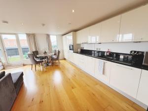 a kitchen with white cabinets and a table with chairs at Fast WiFi, Free Netflix 2 Bedroom Penthouse with Large Balcony in Slough
