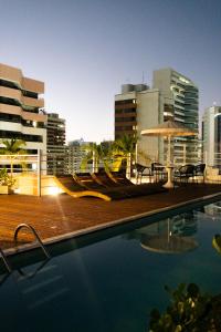 a pool with chairs and an umbrella in a city at D8 Hotel in Fortaleza