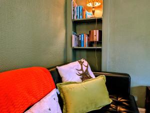 a couch with pillows and a book shelf with books at Scottish Highland Cottage Tyndrum Upper Station in Crianlarich