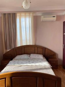1 dormitorio con cama de madera y ventana en Yellow villa in Gonio, en Gonio
