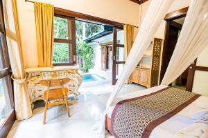 a bedroom with a bed and a desk and a window at villa restu 2 in Ubud
