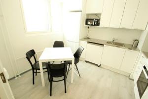 una pequeña cocina con mesa blanca y sillas en Central and Spacious Apartment for 4 with Sauna, en Äänekoski