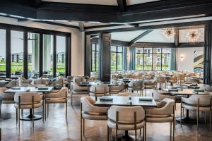 a dining room with tables and chairs and windows at Stylish Golf Course Coach Home in Ave Maria in Harker
