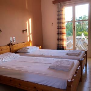two twin beds in a room with a window at Guesthouse Karidia in Skala Eresou