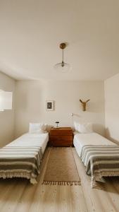 twee bedden in een kamer met witte muren en houten vloeren bij Casa do Miradouro in Évora