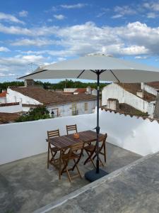 een houten tafel met een parasol op een dak bij Casa do Miradouro in Évora