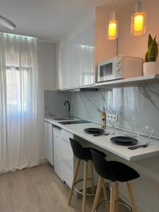 a kitchen with white cabinets and a counter with stools at Alojamiento MEL BEACH in Arinaga