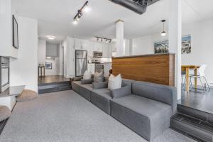 a living room with a gray couch and a kitchen at Slope View Chalet Walk to the Village - Patio in Blue Mountains