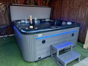 a hot tub with a bottle of wine and two glasses at Acorn Cottage in Ollerton