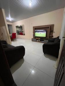 a living room with two couches and a flat screen tv at Casa in Ananindeua