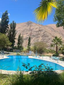 a large blue swimming pool with a mountain in the background at Cabañas Pisco Elqui in Pisco Elqui