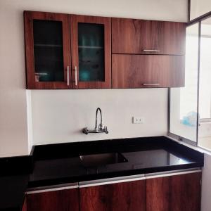 a kitchen with a sink and wooden cabinets at Casa Hogar Andina Huancayo - San Carlos 3 in Huancayo