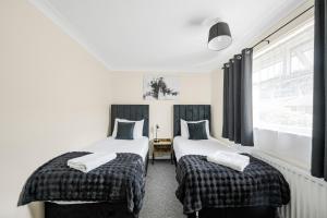 deux lits jumeaux dans une chambre avec fenêtre dans l'établissement The House In Defoe Rd - 3br 1bath W Free Parking, à Ipswich
