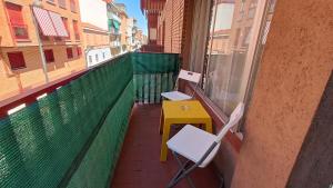 Un balcón con una mesa amarilla y sillas en un edificio en Maravilloso piso en Getafe, Madrid, en Getafe