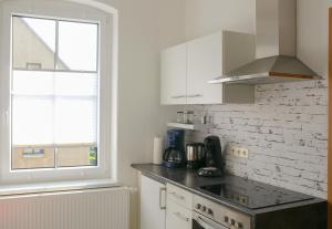 a kitchen with white cabinets and a window at Ferienwohnung Altstadtstube - Zentrale, ruhige Ferienwohnung in der Altstadt von Annaberg-Buchholz - modern & komfortabel in Annaberg-Buchholz