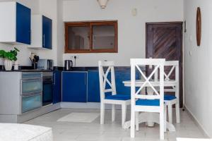 乌昆达LILAC Beachfront 1bedroom Apartment的厨房配有蓝色橱柜和2把白色椅子