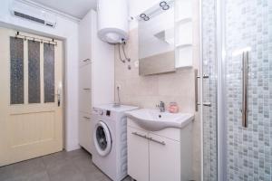 bagno bianco con lavatrice e lavandino di Apartment Vinka near the beach a Postira (Postire)