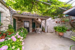 un patio con tavolo, sedie e fiori di Apartment Vinka near the beach a Postira (Postire) Altre 15 foto