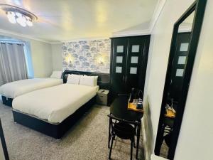 a hotel room with two beds and a table and a mirror at Sachi Hotel in Brighton & Hove