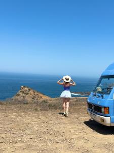 a woman in a hat standing next to a van at rent a Blue Classics's Campervan MB 100 for a van trip in Algarve in Portimão