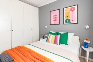 a white bedroom with an orange blanket on a bed at Markowska by VAYA STAYS in Warsaw