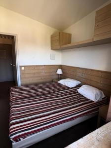 una camera da letto con un letto grande con una coperta a righe di Résidence Le Britania - maeva Home - Appartement 2 pièces 4 personnes - Sélection MAE-6673 a La Tania