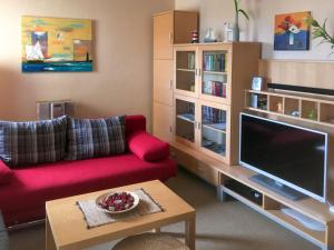 Il comprend un salon doté d'un canapé rouge et d'une télévision à écran plat. dans l'établissement Villa Beethoven mit Ladestation, à Zinnowitz 21 autres photos