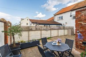 un patio avec une table et des chaises et une clôture dans l'établissement Chalk Reef Cottage - Sheringham Cottages, à Sheringham