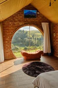 una camera da letto con una grande finestra con un divano e una TV di Rancho La Suiza a Baños