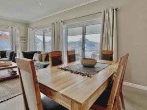 a dining room table with chairs and a living room at Waves Edge at 14 Bridge Waters in Jeffreys Bay