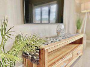 a tv sitting on top of a wooden table with a plant at Waves Edge at 14 Bridge Waters in Jeffreys Bay +32 photos