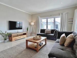 a living room with a couch and a coffee table at Waves Edge at 14 Bridge Waters in Jeffreys Bay