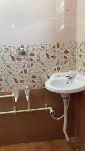 a bathroom with a sink and a wall with a wallpaper at I grand Home Stay in Tallākulam