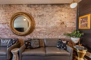 a leather couch in a room with a brick wall at Chic Home with King Bed and Fire Pit in Pittsburgh