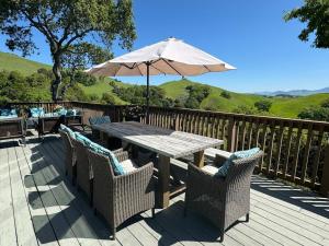 a wooden deck with a wooden table with an umbrella at Relax and Rejuvenate- Lafayette Treehouse with Cave Spa, Waterfall, and Incredible Views in Lafayette