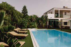 a swimming pool with lounge chairs and a house at Surfescape Fuerteventura in Lajares