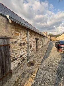 een stenen gebouw met een auto ernaast bij Maison de campagne proche D'Angers in La Meignanne