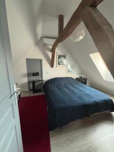 een slaapkamer met een blauw bed op een zolder bij Maison de campagne proche D'Angers in La Meignanne +4 foto's