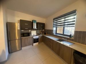 una cucina con mobili in legno e un frigorifero in acciaio inossidabile di Room Cozy in San Julian 2 a San Giuliano