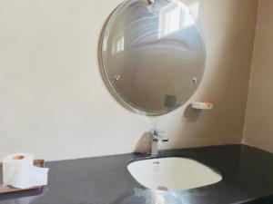 a bathroom with a round mirror and a sink at The Masken Murree in Murree