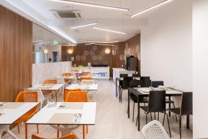 a dining room with tables and chairs and a kitchen at The ICONS Lisbon Hotel in Lisbon