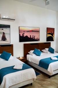 two beds in a room with pictures on the wall at Hotel Albemarle Galapagos Beachfront in Puerto Villamil