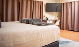 a bedroom with a bed with a chair and curtains at Staybridge Chobe Safari Resort in Kasane