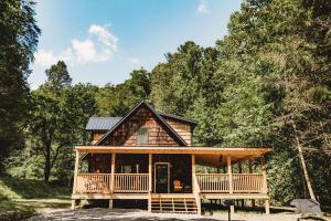 Una cabaña en el bosque con un porche envolvente. en Creekside Cabin, en Pigeon Forge
